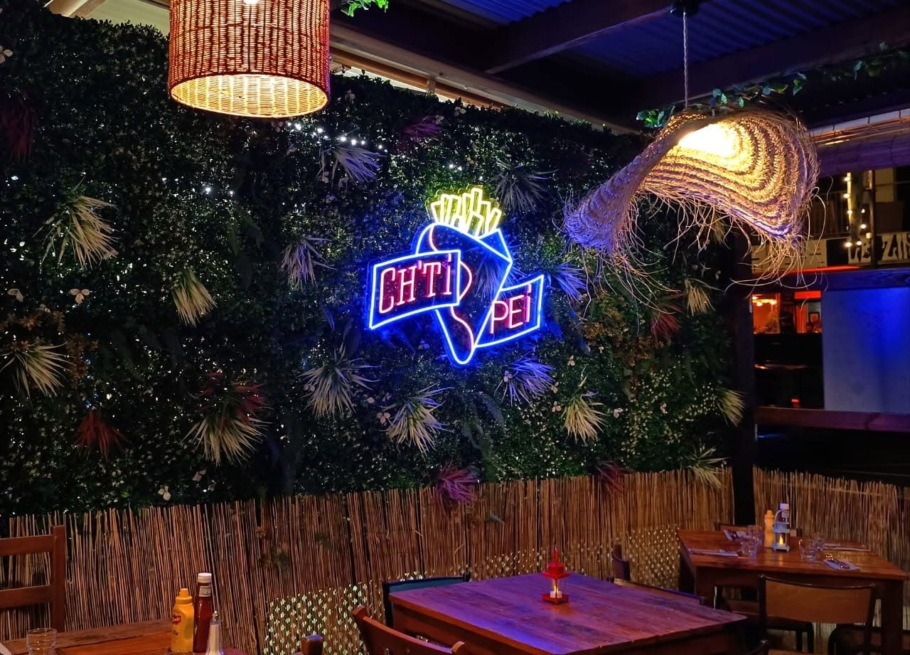 La terrasse du Chti Péi le soir, enseigne néon et mur végétal